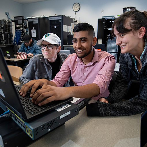 Three students working on a computer in a server room