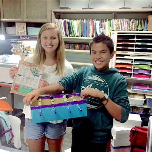 Two youth students holding up their art projects