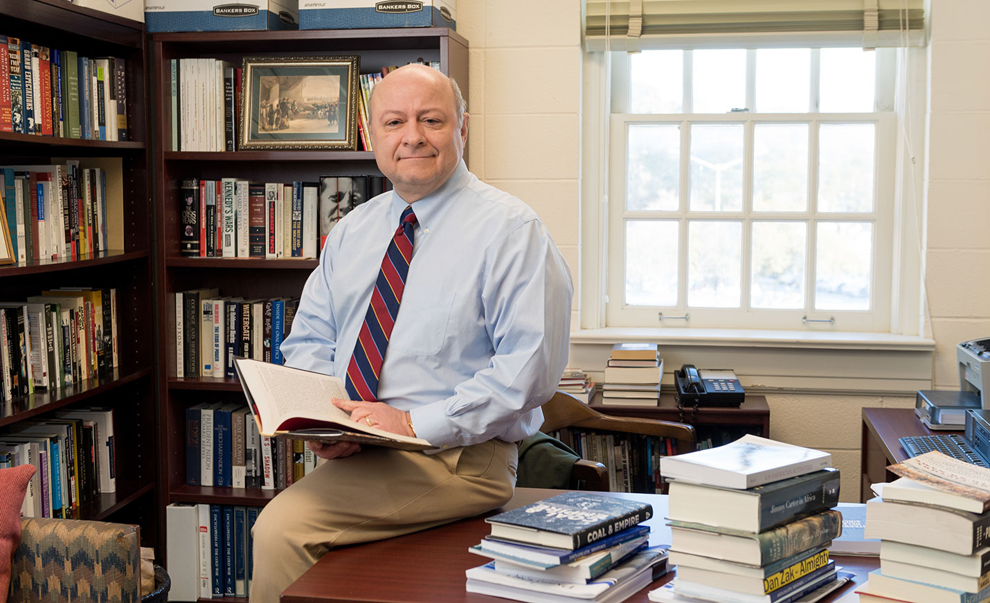 Professor sitting on a desk with an open book
