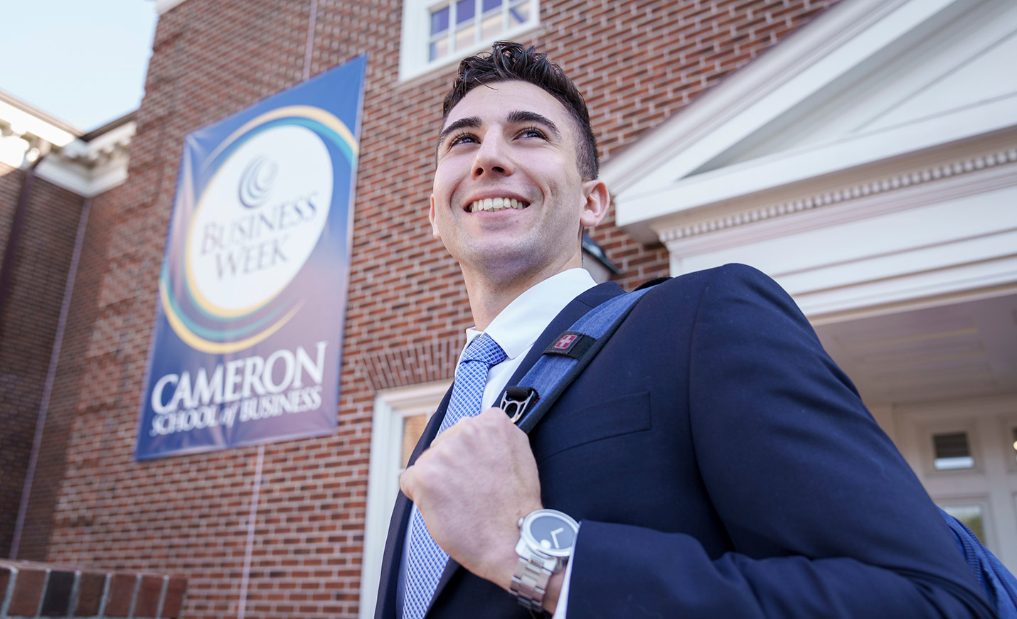 A student in a blazer standing outside of Cameron Hall