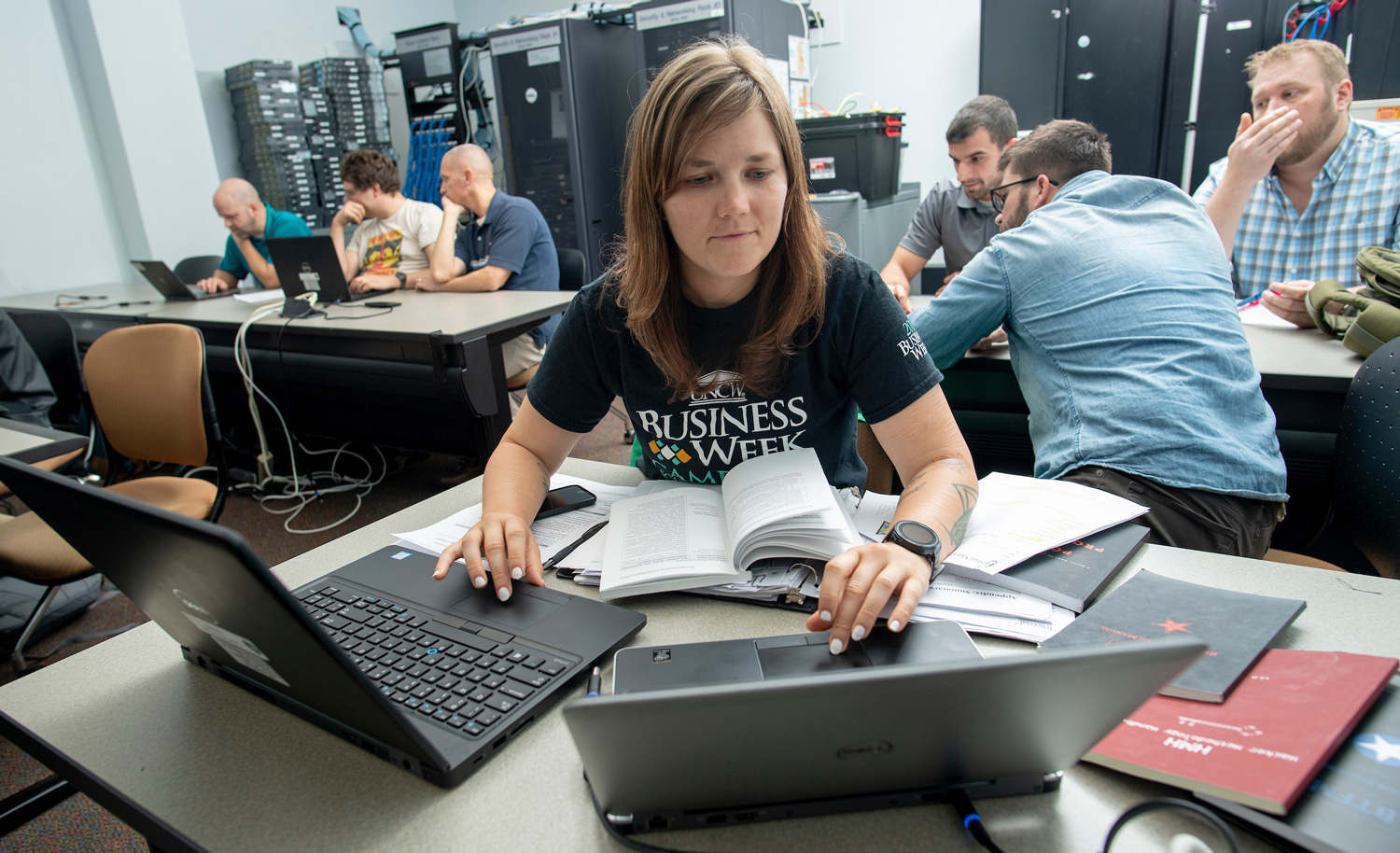 Student working a tech lab on campus with two lap tops and books