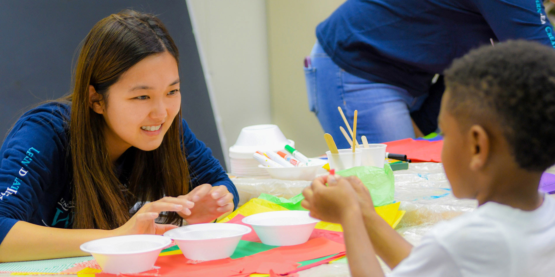 Student helps young child with painting project
