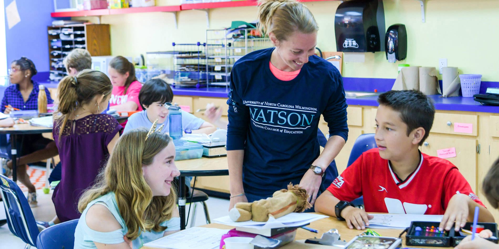Student helps children in classroom.
