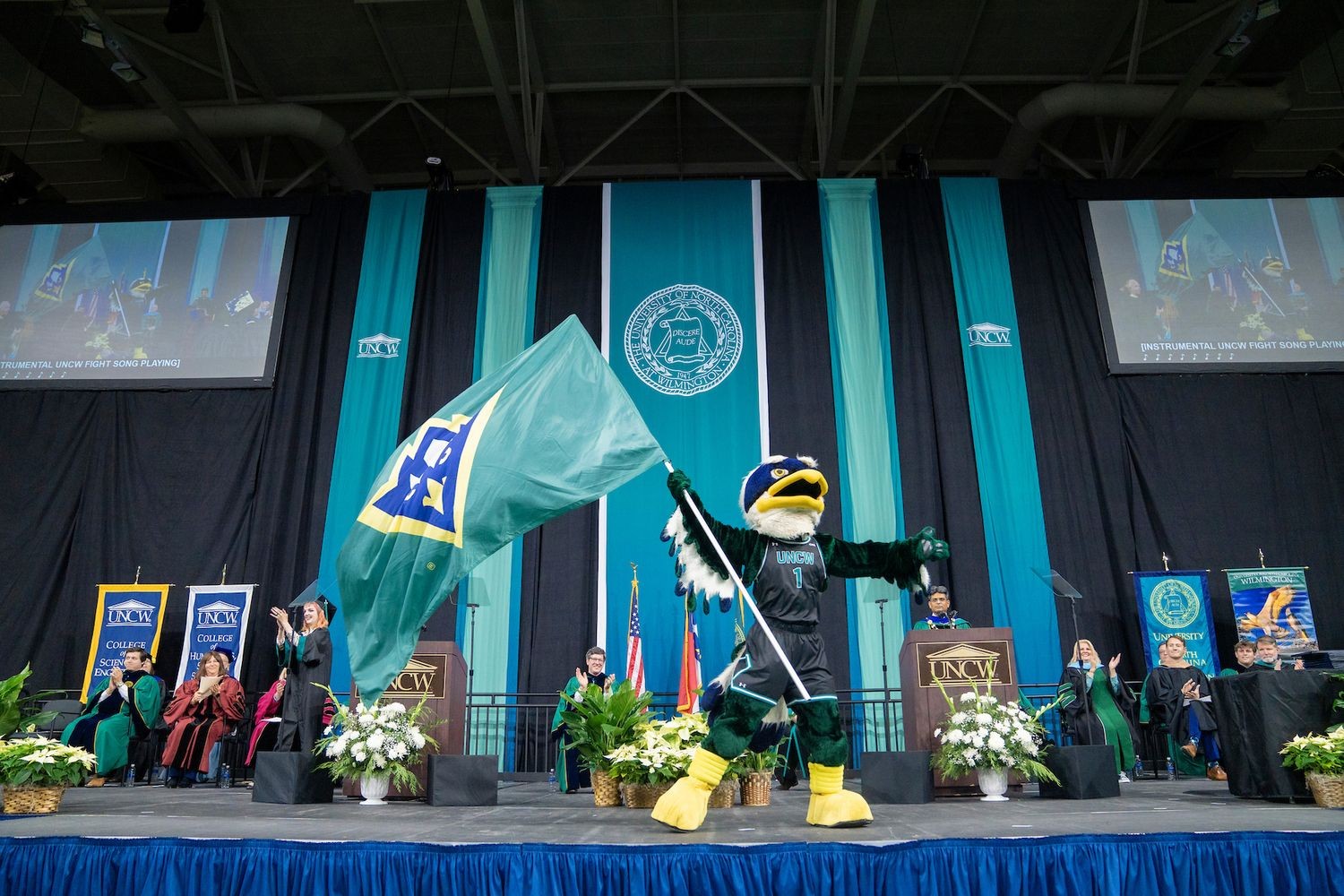 Mascot, Sammy C. Hawk waves flag at commencement