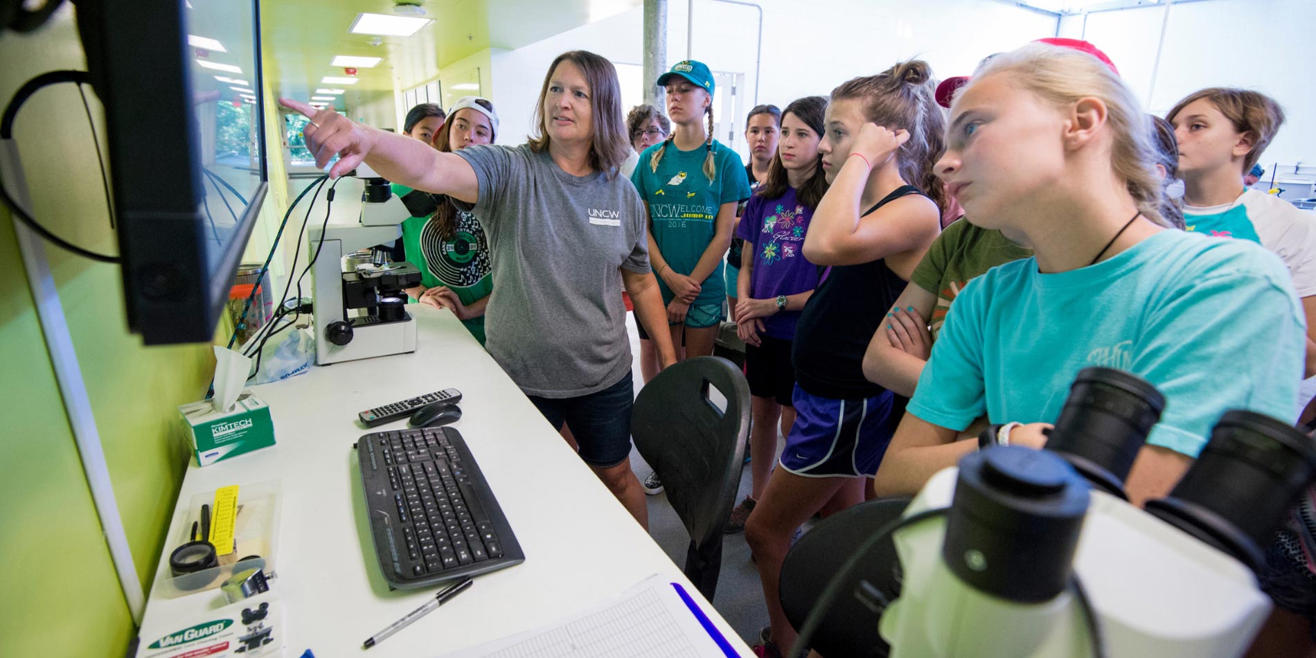 Secondary students looking at the view of a microscope on a large TV