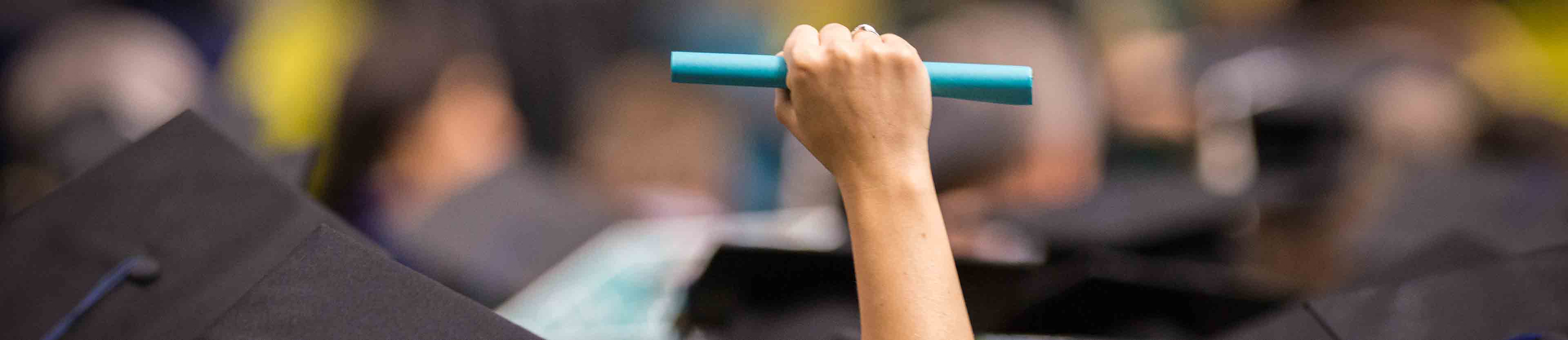 Hand holding a rolled diploma in the air