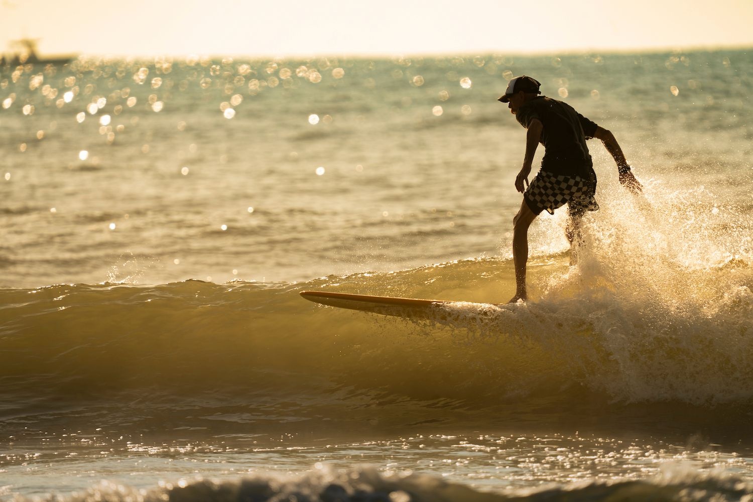 Surfer riding a wave while the sun is setting